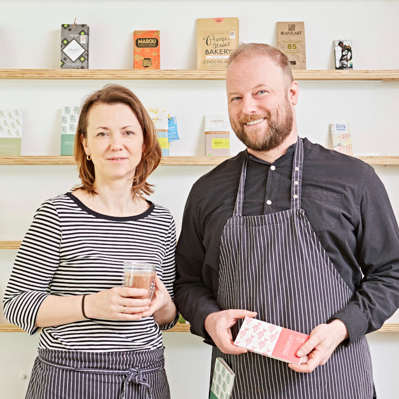 Mike & Becky mit Schokoladentafel in der Hand in ihrem Café in Brüssel